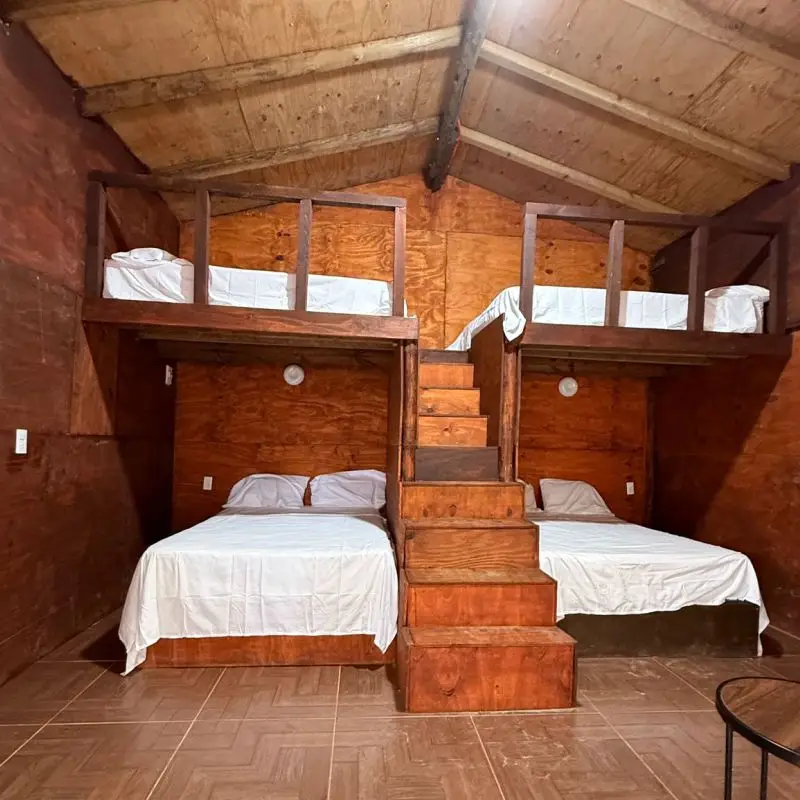 Cuatro camas matrimoniales en habitaciones tipo tapanco de madera en Cabaña Don Moy Chachalacas.